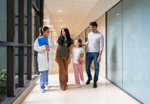 Family walking with doctor in hospital corridor.